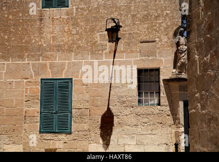 Vue paysage de pierre mur avec fenêtre d'obturation et lampe ombre pris dans Mdina Malte Banque D'Images