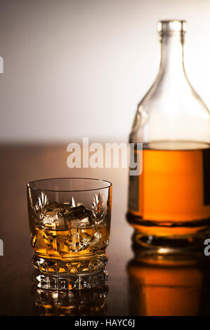 Whisky avec glace en verre et la bouteille sur fond de bois Banque D'Images