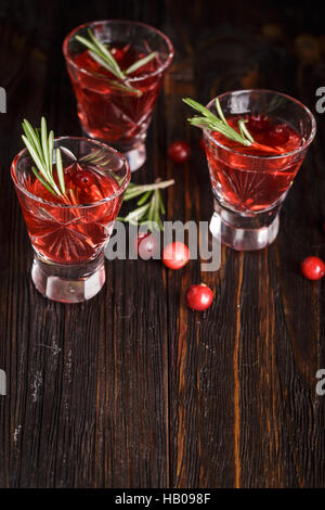 Trois verres de boissons rafraîchissantes avec cocktail de canneberges canneberges baies, de romarin et de branches d'épinette à l'arrière-plan sur un sol en bois backgrou Banque D'Images