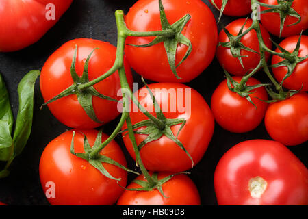 Branche de tomates rouges sur noir, de l'alimentation vue d'en haut Banque D'Images