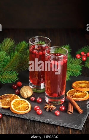 Cocktail de canneberges de Noël décoré avec des bâtons de cannelle, d'anis étoile, sécher les tranches d'orange et de branches de sapin Banque D'Images
