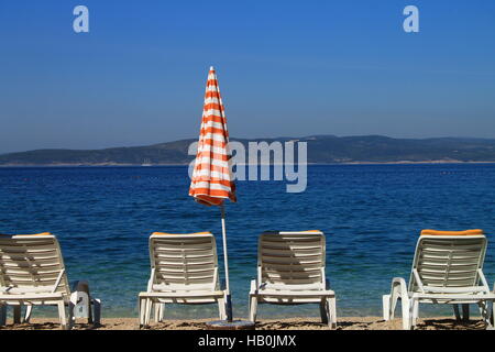 Plage de sable blanc de quatre chaises et parasol, près de la mer Adriatique à Brela, Croatie Banque D'Images