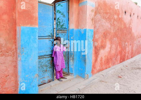 Saint-louis, Sénégal - le 17 octobre 2014 : local boy stands à son domicile.s ferme la porte en la ville coloniale après le retour de l'école dans l'après-midi Banque D'Images