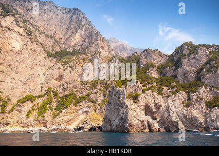 Paysage avec côte rocheuse de l'île de Capri, Mer Méditerranée, l'Italie. Petit bateau de plaisance entre dans la grotte côtière Banque D'Images