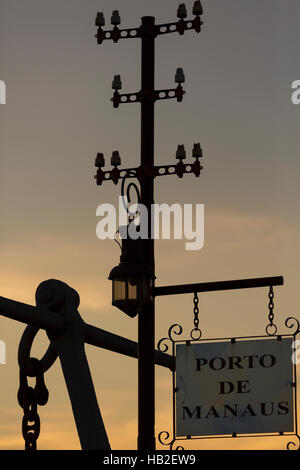 Silhouette de vieux pylônes électriques et panneau avec Porto de Manaus écrit en portugais (port de Manaus) pendant un coucher de soleil à Manaus Banque D'Images