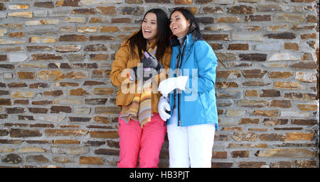 Cute twins en manteaux d'hiver leaning on wall Banque D'Images