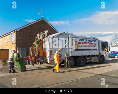 Les hommes qui travaillent à l'arrière d'un véhicule d'élimination des déchets vidange d'un wheelie bin de déchets ménagers pour le recyclage pick up dog poo Banque D'Images