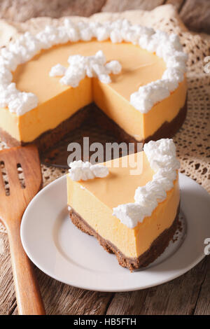 Un morceau de gâteau au fromage à la citrouille avec crème fouettée close-up sur une plaque sur la table. La verticale Banque D'Images