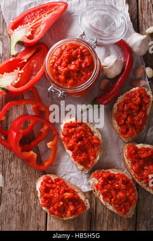 Ajvar dans un bocal en verre et de grillé sur un fond de bois vertical Vue de dessus. Banque D'Images