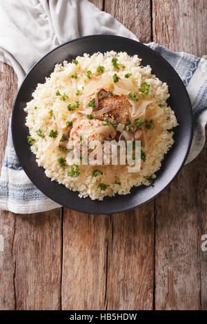 Poulet Yassa avec oignons et garni avec du couscous close up sur une assiette. vertical Vue de dessus Banque D'Images