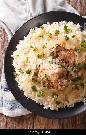 Poulet Yassa avec compote d'oignons marinés et de couscous close up sur une assiette. vertical Vue de dessus Banque D'Images