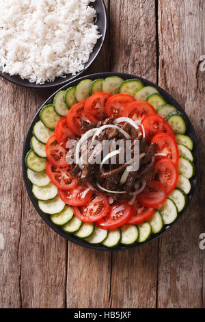 La nourriture cambodgienne : boeuf Lok Lak avec légumes frais et un plat de riz sur la table. Vue verticale d'en haut Banque D'Images