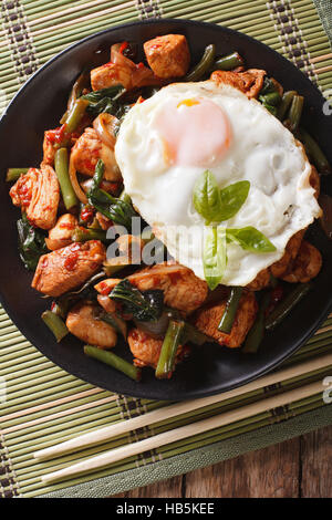 Poulet sauté au basilic, haricots verts et un œuf frit sur un plateau de près. La vue verticale d'en haut Banque D'Images