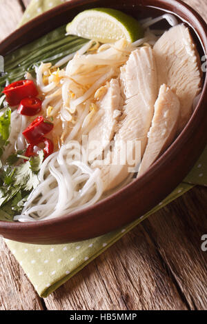 Soupe vietnamienne pho ga avec poulet et nouilles de riz dans un bol close-up vertical. Banque D'Images