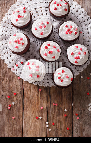 Red Velvet cupcakes fraîchement sur une serviette lacy close-up sur la table. vertical Vue de dessus Banque D'Images