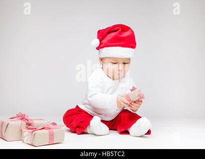 Adorable jeune baby boy wearing a Santa hat ouverture des cadeaux de Noël Banque D'Images