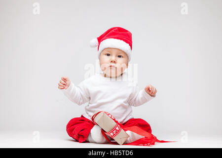 Adorable jeune baby boy wearing a Santa hat ouverture des cadeaux de Noël Banque D'Images