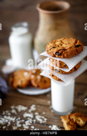 Des biscuits aux noix et raisins secs et verre de lait sur fond de bois foncé, gros plan, selective focus Banque D'Images