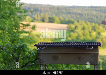 Barbecue portable vide en face d'un paysage d'été vert frais Banque D'Images
