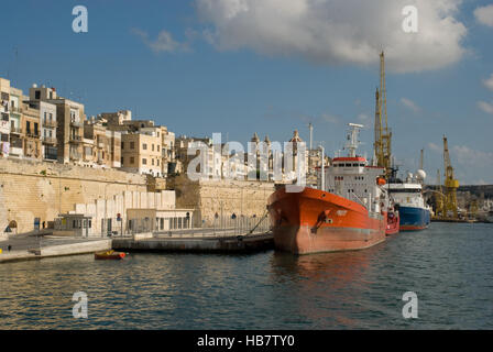 Côté port de Seguela Bay sur l'île de Malte montrant des navires à l'ancre et des bâtiments portuaires et des grues de déchargement en arrière-plan Banque D'Images