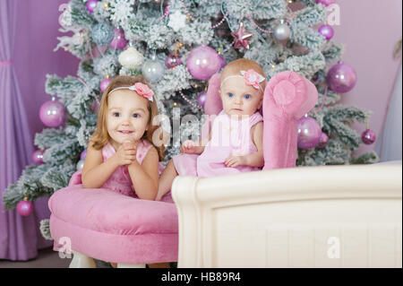 Deux soeurs à la maison avec l'arbre de Noël. Portrait des enfants heureux pour décorations. Banque D'Images