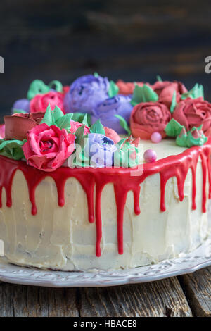 Gâteau avec glaçage au chocolat rouge et fleurs. Banque D'Images