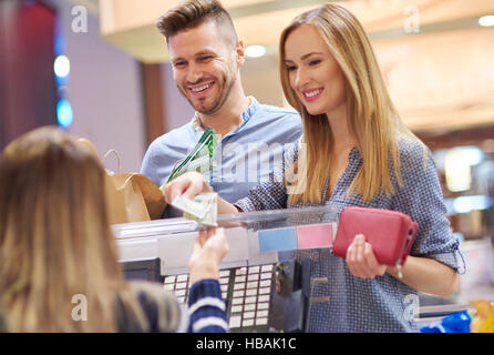 Jeune femme de payer en argent comptant en magasin Banque D'Images