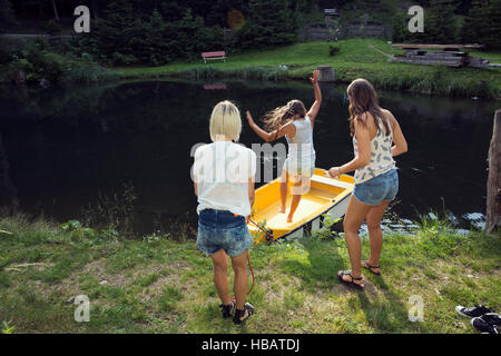 Trois amis femelles adultes de sauter dans le bateau à rames sur le lac, Sattelbergalm, Tirol, Autriche Banque D'Images