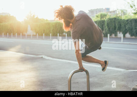 Jeune homme hipster des coups de talons sur le trottoir jusqu'au soleil Banque D'Images