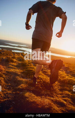 Homme qui court sur la falaise au coucher du soleil, Keimiotunturi, Laponie, Finlande Banque D'Images