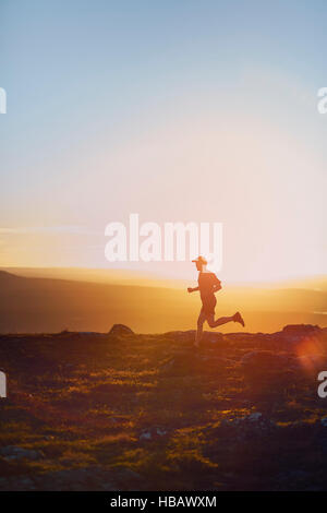 Homme qui court sur la falaise au coucher du soleil, Keimiotunturi, Laponie, Finlande Banque D'Images