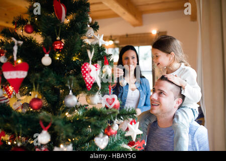 Jeune famille avec daugter à arbre de Noël à la maison. Banque D'Images