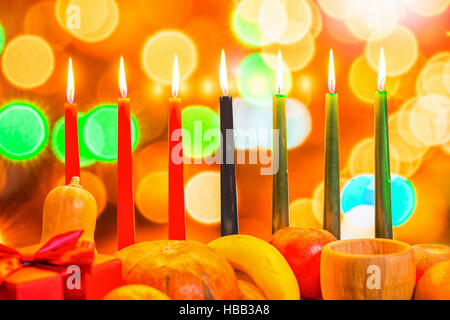 Kwanzaa africaine avec concept de fête décorer sept bougies rouge, noir et vert, boîte-cadeau, citrouille, bol et fruits sur fond flou flou léger, cl Banque D'Images