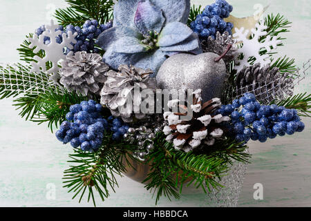 Noël arrière-plan avec les poinsettias en soie bleu et le scintillement des baies. Arrangement de fleurs de Noël artificiel avec des pommes de pin et branches de sapin. Maison de Vacances Banque D'Images