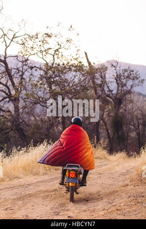 Man riding motorbike, enveloppé dans une couverture, vue arrière, Sequoia National Park, Californie, USA Banque D'Images