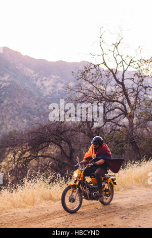 Man riding motorbike, enveloppé dans une couverture, Sequoia National Park, Californie, USA Banque D'Images