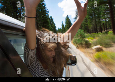 Young woman leaning out de déménagement car window, Mammoth Lakes, California, USA Banque D'Images