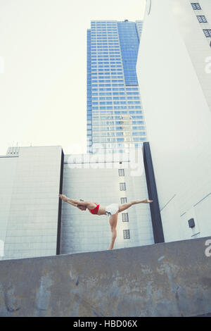 Jeune femme à l'extérieur, Standing on wall in yoga position Banque D'Images