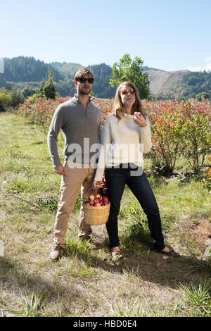 Portrait of mid adult couple avec panier de pommes cueillies dans ferme bio verger Banque D'Images