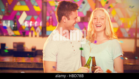 Image composite de l'heureux couple toasting beer bottles Banque D'Images