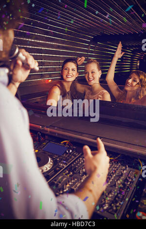 Image composite de disc-jockey à jouer de la musique avec trois femmes dansant sur la piste de danse Banque D'Images