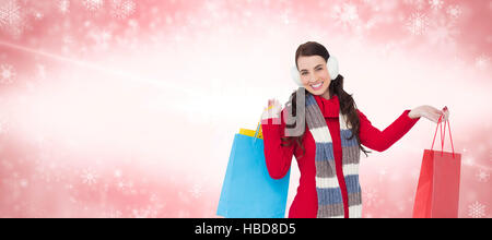 Image composite de brunette in winter clothes holding shopping bags Banque D'Images