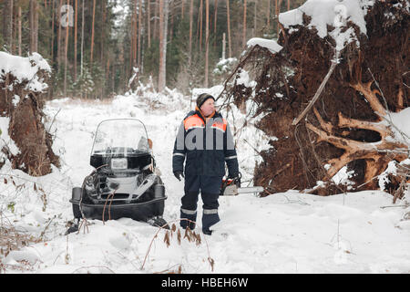 Bûcheron Proffesional tenir scie à main. Le port de vêtements de protection d'hiver à l'aide de tronçonneuse. nettoyer les arbres tombés Banque D'Images