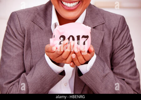 Image composite de close up of a smiling businesswoman holding a piggybank Banque D'Images