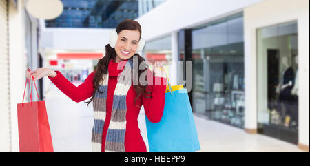 Image composite de brunette in winter clothes holding shopping bags Banque D'Images