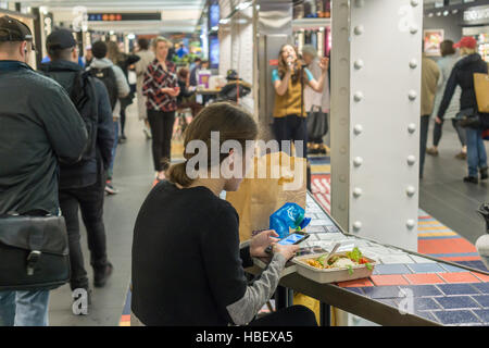 Une femme prend une pause déjeuner comme Hannah Florence, un spectacle dans le Cirque du Soleil's musical de Broadway 'amant', chante des chansons de la comédie musicale à une midi performance dans Turnstyle, un centre commercial et de foodie arcade dans le métro à New York le Mardi, Novembre 29, 2016. 'Amant' est au Lyric Theatre et est au sujet de l'âge d'or de Hollywood. (© Richard B. Levine) Banque D'Images