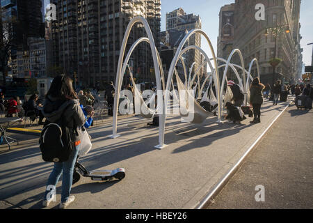 Les visiteurs de Flatiron Plaza à New York Lundi, Novembre 28, 2016 'interagir avec Sky-Line Flatiron' créé par beaucoup d'architectes. L'installation de Noël est l'élément central de la 23e Rue du Flatiron Partenariat maison de la programmation. Les dix arcs lumineux avec des hamacs suspendus sous impliquer les visiteurs de se détendre et de contempler les merveilles architecturales du quartier, en particulier le Flatiron Building. (© Richard B. Levine) Banque D'Images