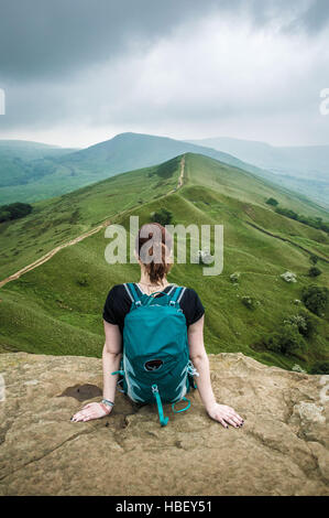 Femme assise sur un promontoire rocheux, Peak District, Derbyshire, Royaume-Uni. Banque D'Images