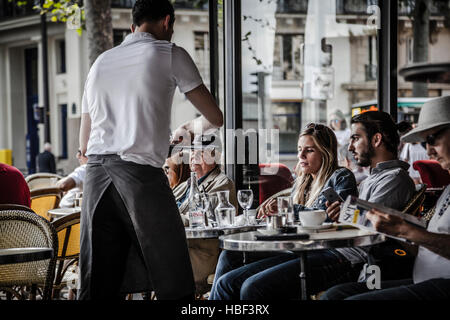 Waiter serving clients au café parisien traditionnel en plein air dans le centre ville. Banque D'Images