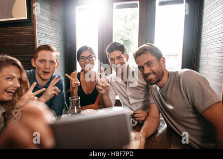 Les gens s'amuser à multiraciale en prenant un café avec selfies téléphone mobile. Groupe de jeunes amis assis au restaurant taking self portrait avec smart Banque D'Images